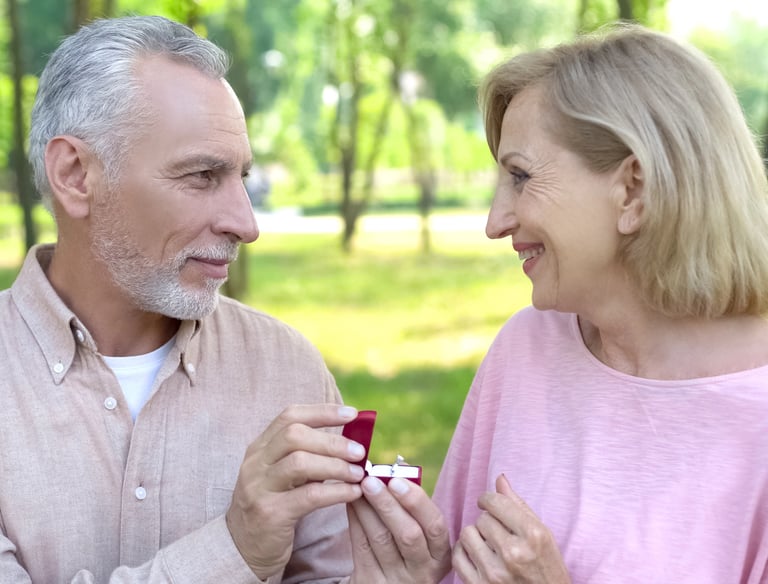 a man and woman are smiling and holding a ring