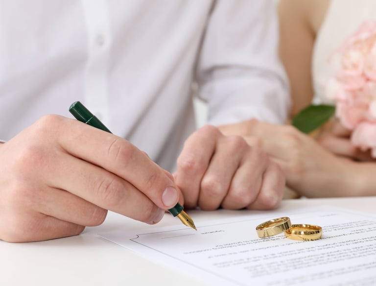a man and woman holding wedding rings and signing license