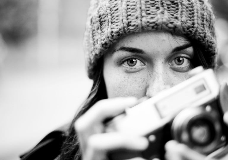 Student in fine art photography courses holding a vintage camera, black and white portrait.