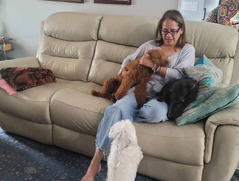a woman sitting on a couch with two dogs for an overnight boarding