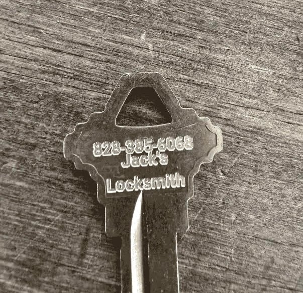 Metal key engraved with "Jack's Locksmith" and phone number, representing professional locksmith services.