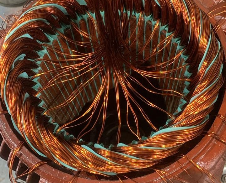 Um motor elétrico aberto, mostrando os fios de cobre da rebobinagem, com sobras de ligação.