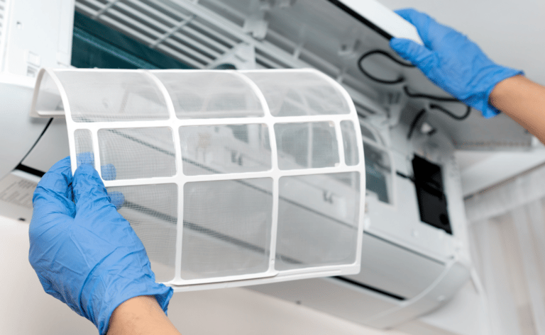 Una persona con guantes sosteniendo un filtro de aire acondicionado