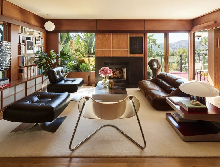 Modern living room with leather furniture and large windows.