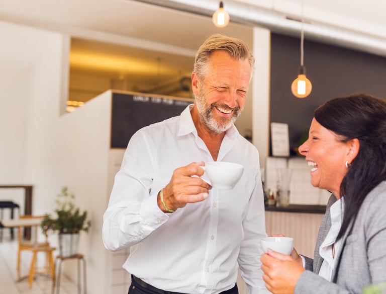Two office colleagues drinking coffee and laughing