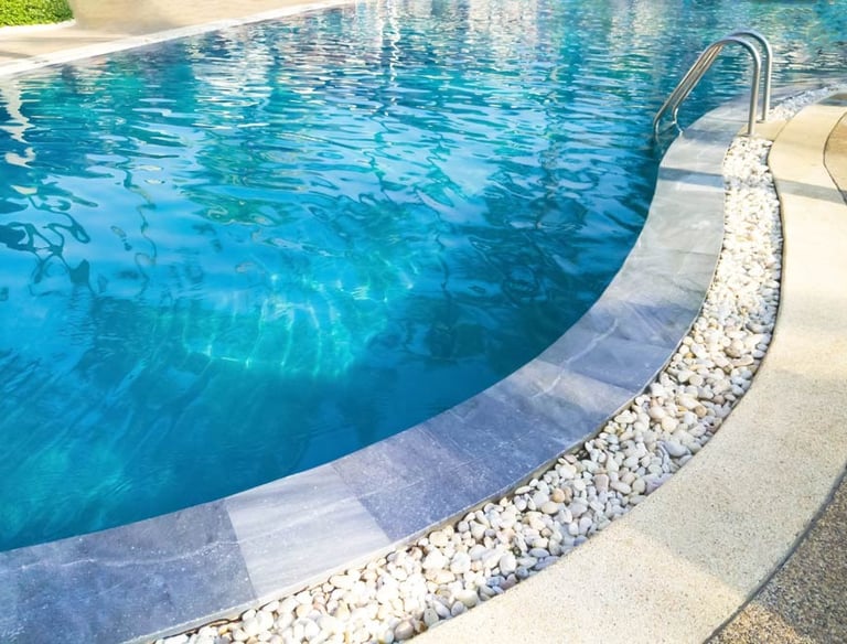 Curved backyard pool with clean blue water and pebble-lined edge, maintained by Piscus Pools in Los Angeles.