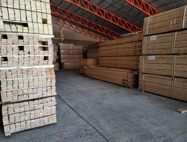 Stacks of industrial lumber and wood planks stored in a large warehouse facility.