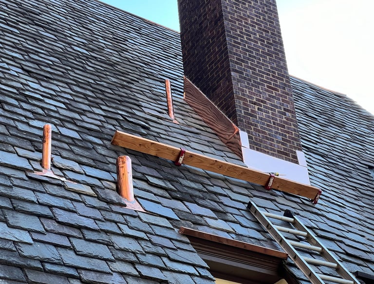 Professional roof repair featuring new copper flashing installed around a brick chimney and vent pipes.
