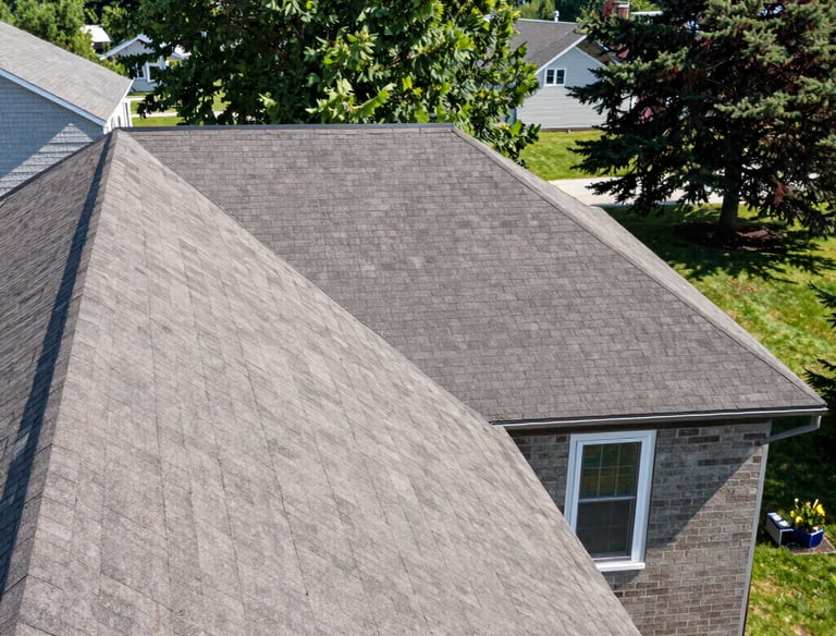 Close-up of a sturdy roof with fresh shingles under a clear blue sky.