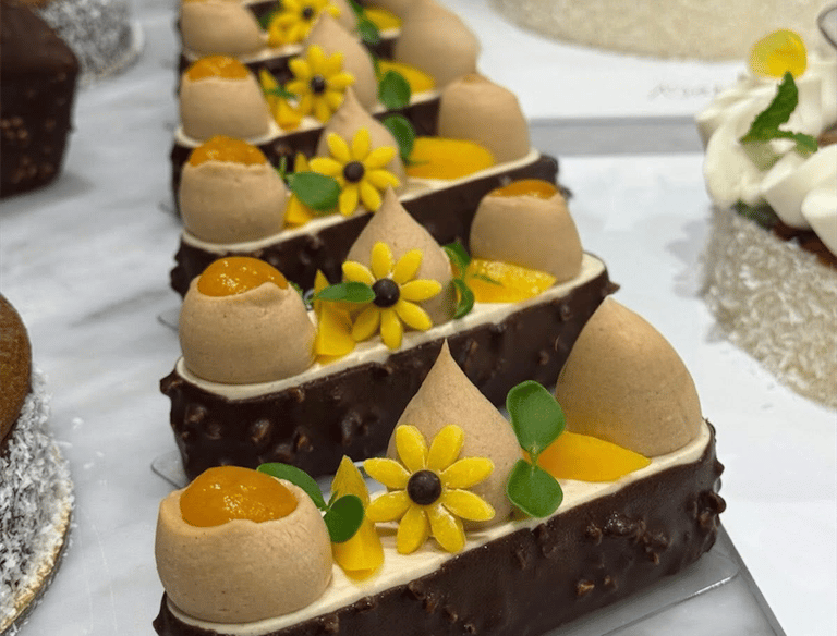 Gourmet chocolate hazelnut mousse cakes with mango filling and yellow flower decorations.
