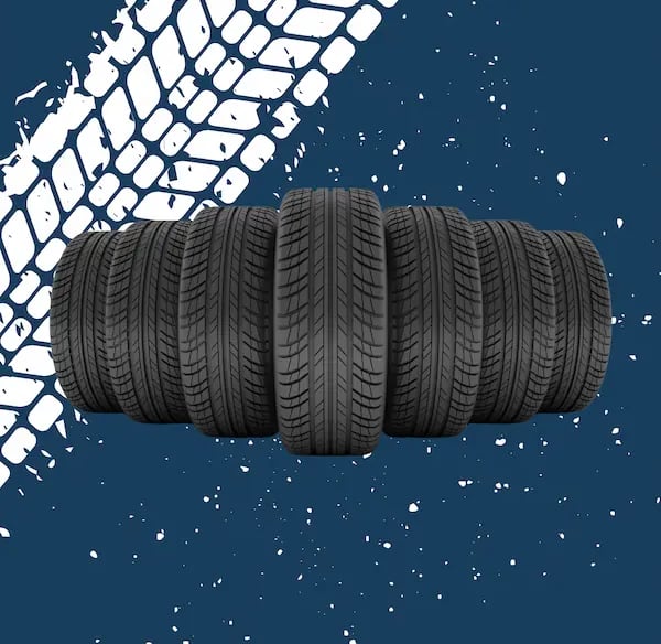 Seis neumáticos de coche nuevos con banda de rodadura visible, dispuestos en fila sobre un fondo azul oscuro con salpicaduras