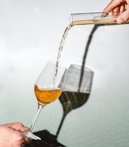 a person pouring a glass of wine into a glass