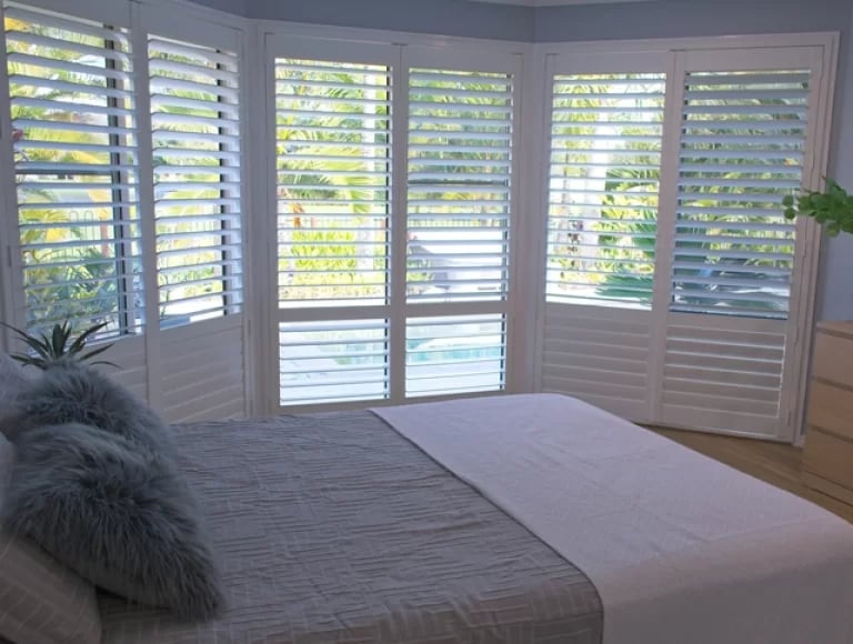 Bay window shutters fitted in a bedroom
