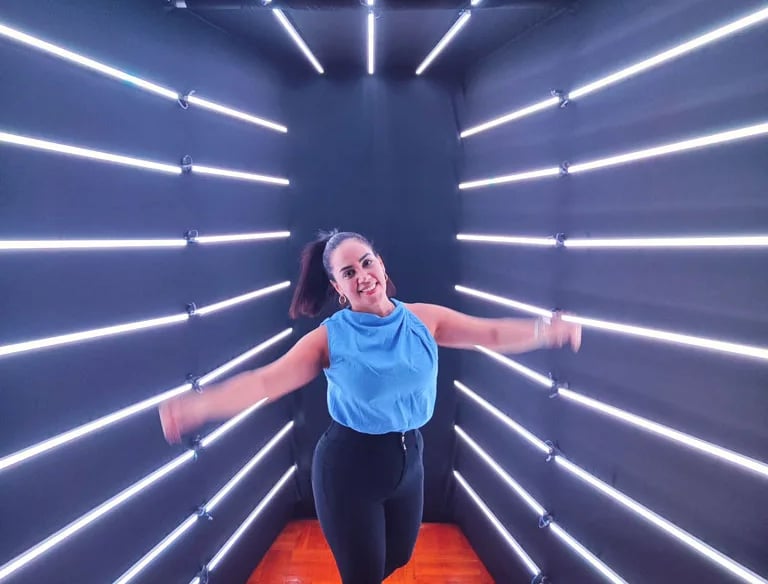 a woman in a blue top and black leggings and a blue top in a led backdrop tunnel
