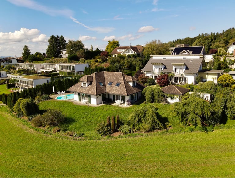 Drohnenaufnahme eines Einfamilienhauses mit Garten, Pool und umliegender Wohngegend