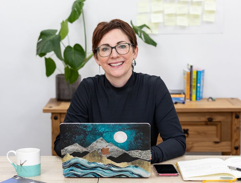 a woman sitting at a desk with a laptop computer