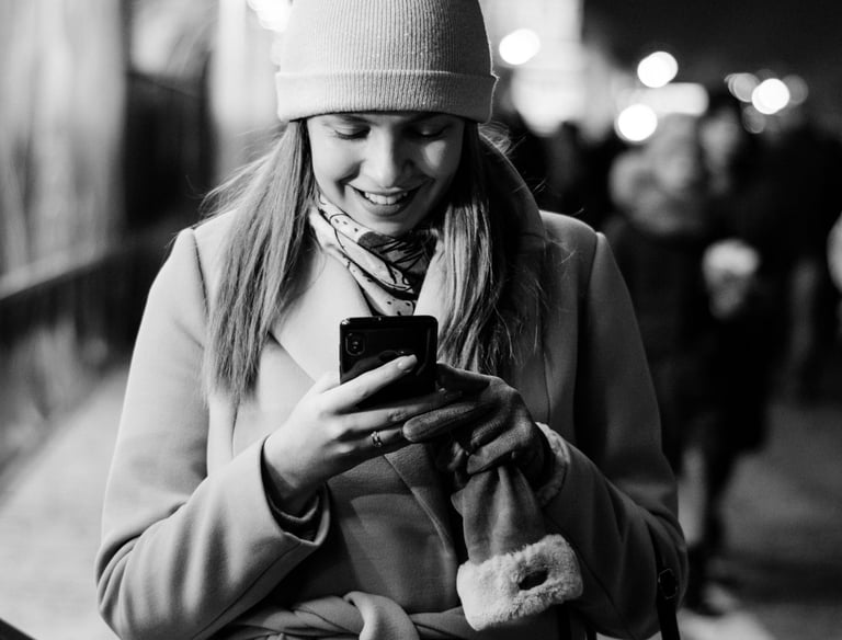 Eine Frau in Mantel und Hut schaut auf ihr Telefon
