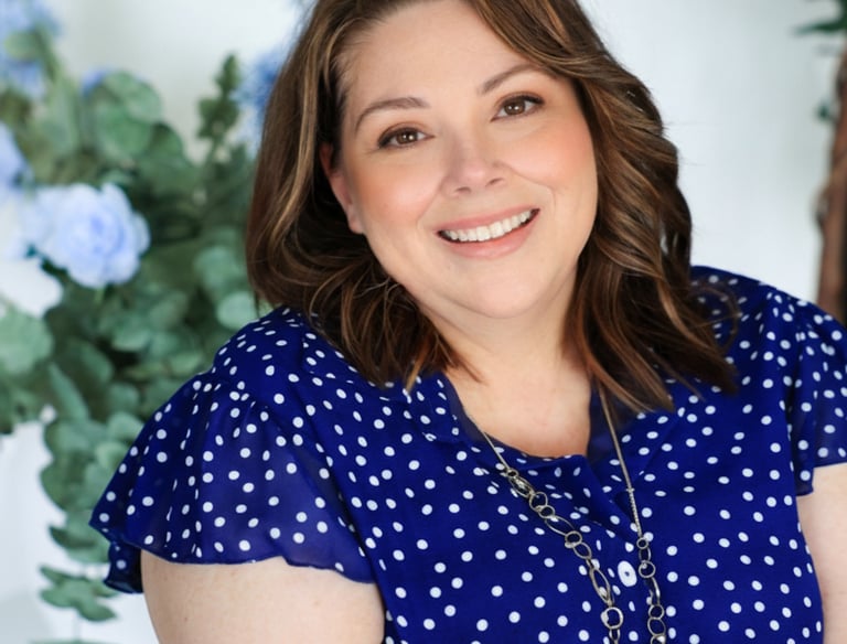 a woman in a blue dress smiling and holding a flower
