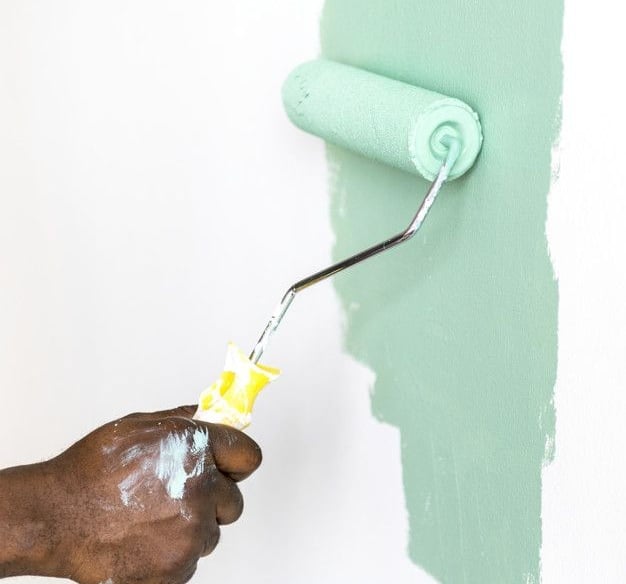 a person painting a wall with a roller roller