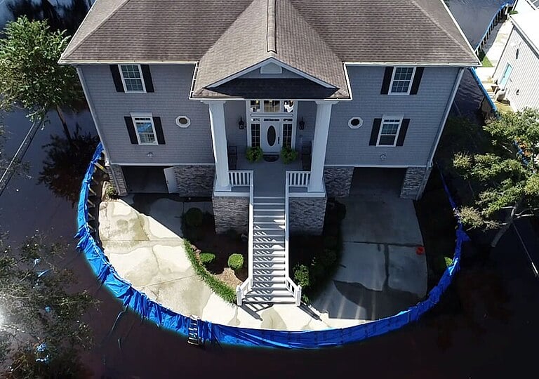 Coastal home protected by modular temporary flood barrier panels during high water