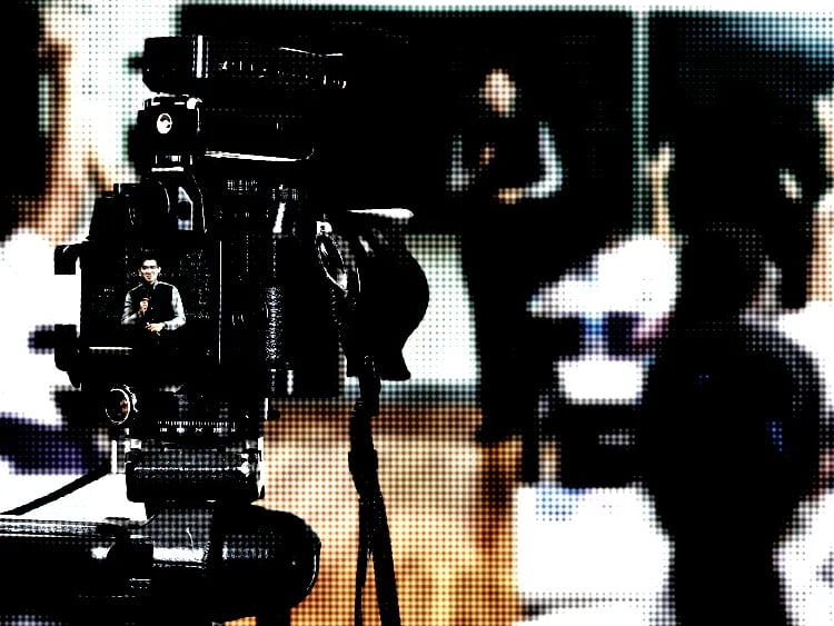 Film camera facing educator with students,