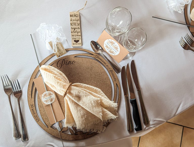 Rustic wedding table setting with personalized wooden placemat, linen napkin, and elegant silverware.