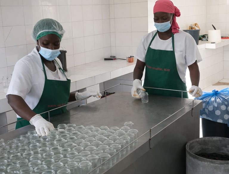 Two female food processing workers in hairnets and masks organizing glass jars in a clean facility.