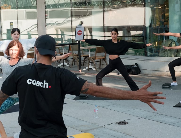 A diverse fitness group practices yoga poses during an outdoor class with a coach.