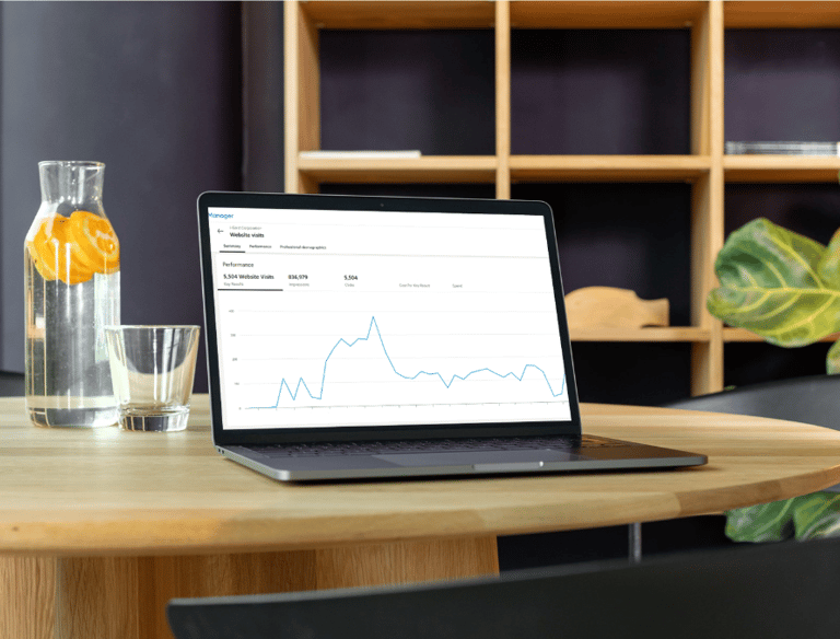 Laptop on a wooden table displaying a business analytics dashboard with website traffic performance charts.