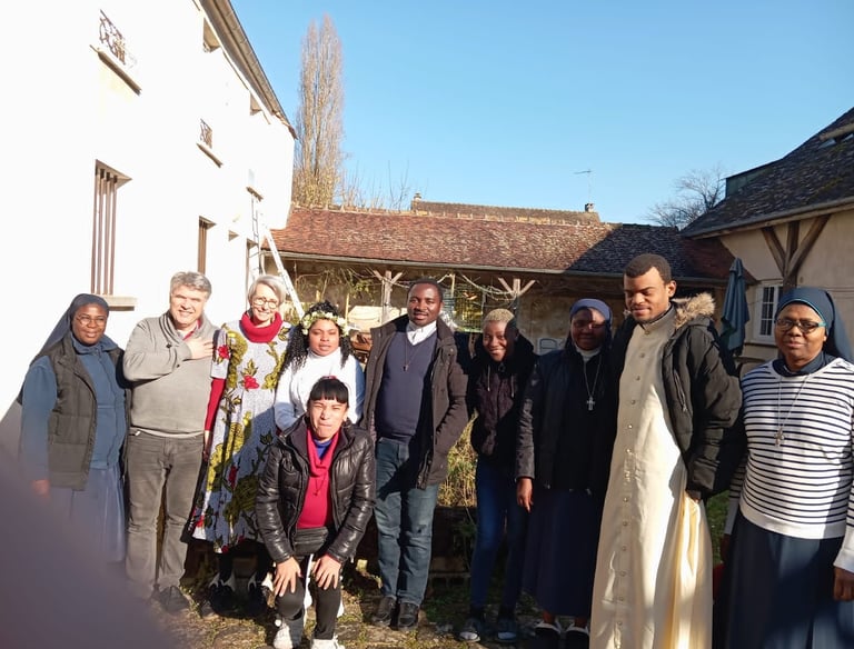 A diverse group of Catholic nuns and priests standing together in a sunny courtyard for a community photo.