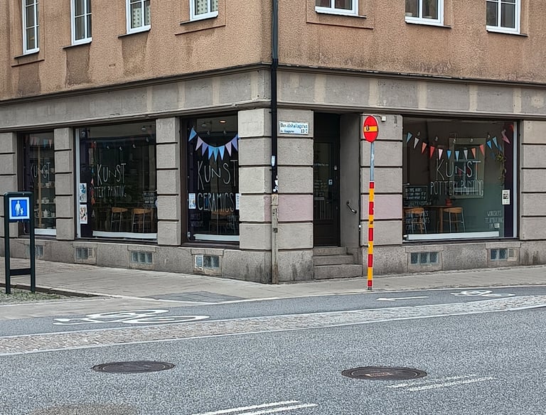 Pottery painting cafe storefront windows showing chairs and tables inside.