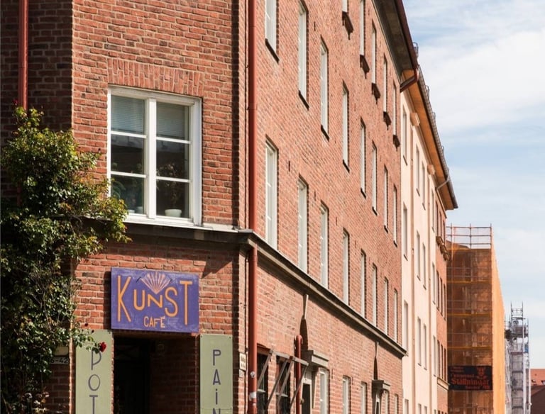 "Kunst Cafe" exterior with brick walls, signs, and outdoor tables.
