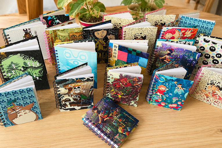 Colección de cuadernos de espiral con diseños de anime de Studio Ghibli y One Piece sobre una mesa d