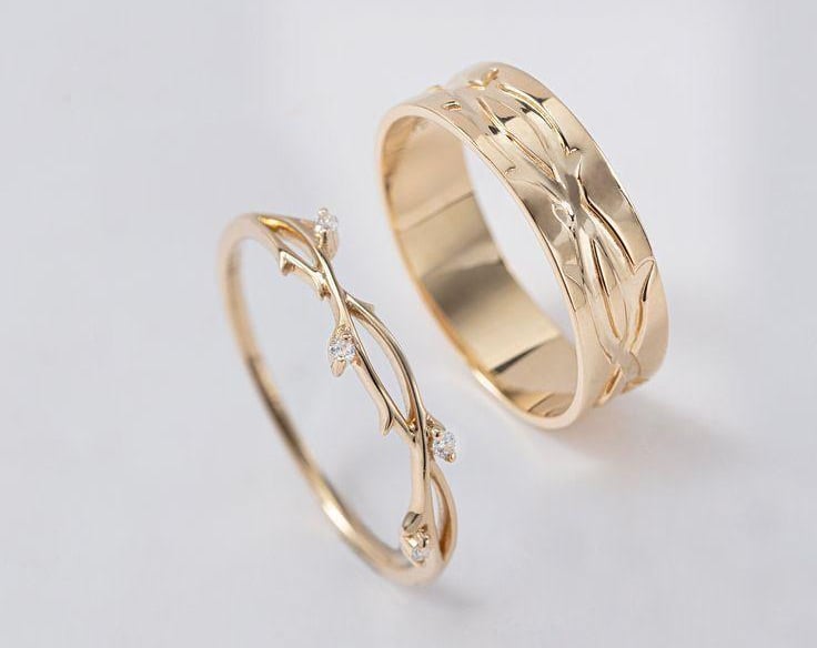 Elegantes alianzas de boda a juego en oro, inspiradas en la naturaleza con grabados de enredaderas.