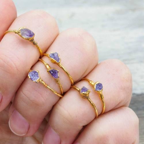 Mano con cinco delicados anillos de oro, cada uno con cristales de amatista púrpura