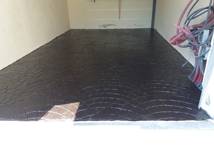 Superficie de hormigón impreso en color negro con diseño semicircular, ideal para parkings y zonas de almacenamiento."