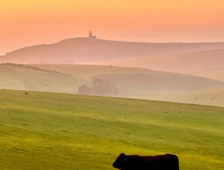view towards Belle Tout over mist covered downs at sunset