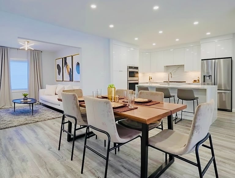 Modern open concept kitchen and dining room with a wood table and white cabinets.