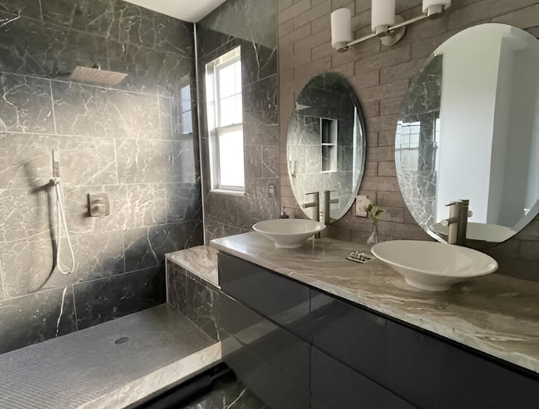 Modern bathroom featuring dark marble tiles, a walk-in shower, and a double vanity with vessel sinks.