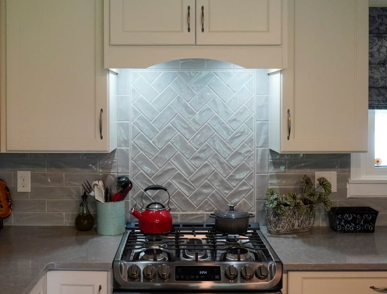 a stove with hood under the cabinet with LED lights to iluminate the wall backsplash