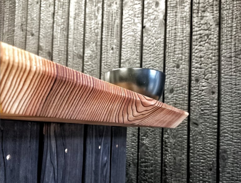 Live edge wooden countertop with grain texture against a charred Shou Sugi Ban wood wall.