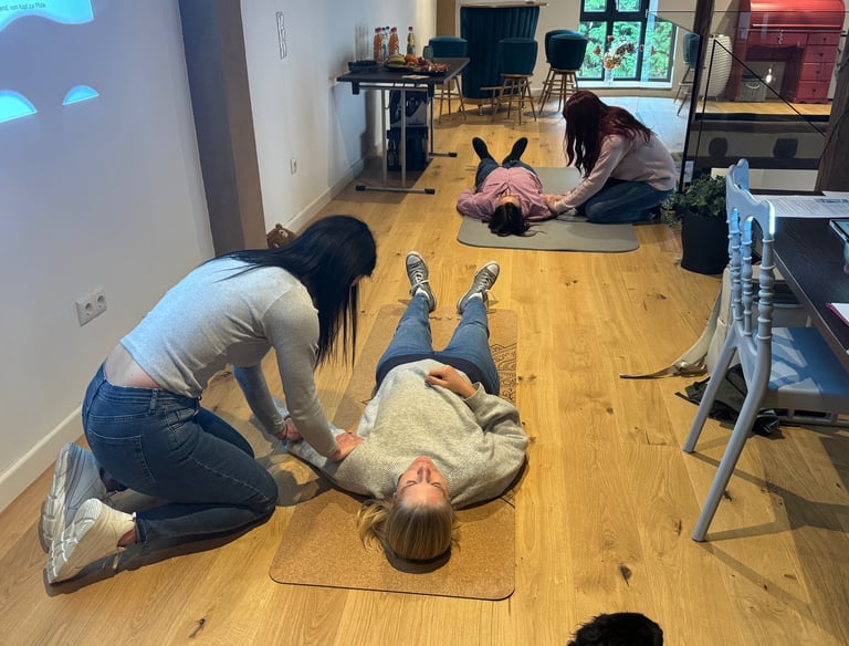 Zwei Menschen liegen auf einer Matte, während sie von anderen Menschen eine Shiatsu-Behandlung bekom