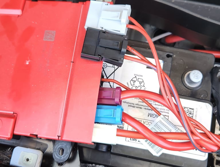 BMW car battery with electrical components attached 