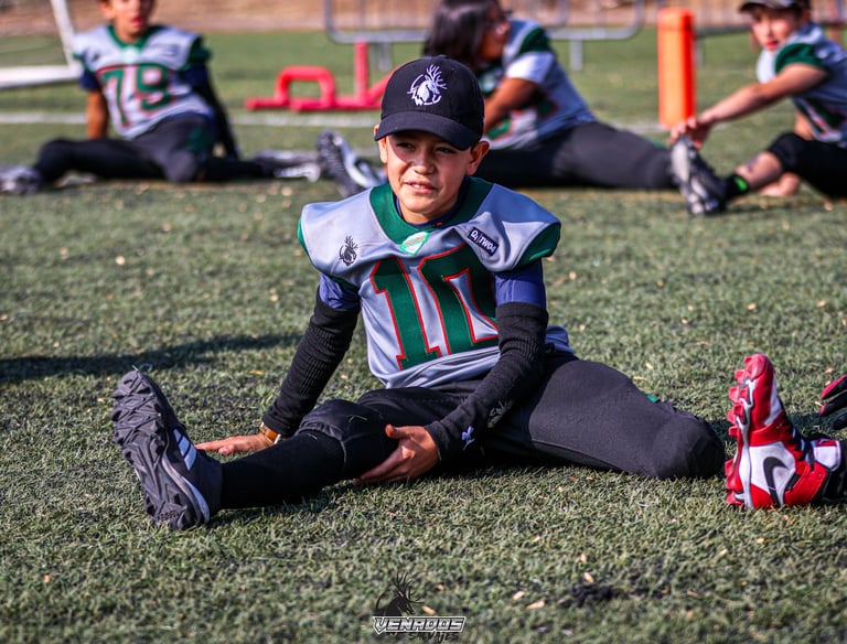 Joven miembro del equipo de football americano estirando