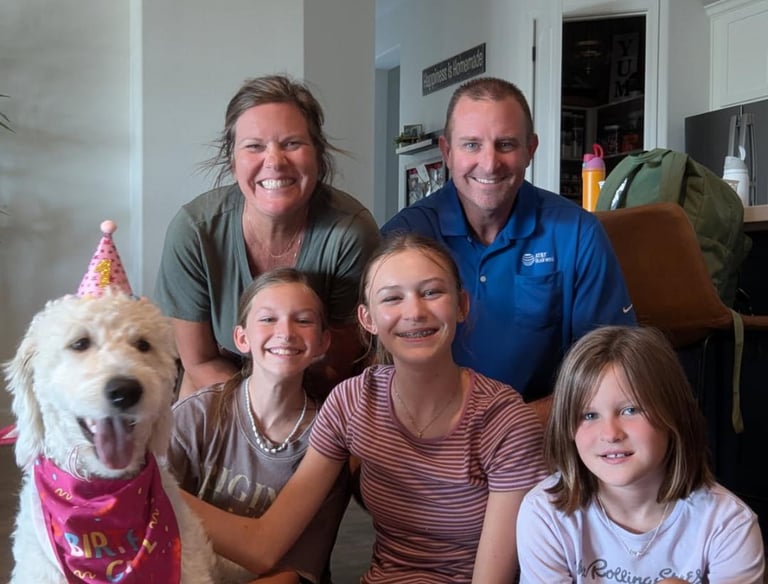 Family smiling at their new home with dog