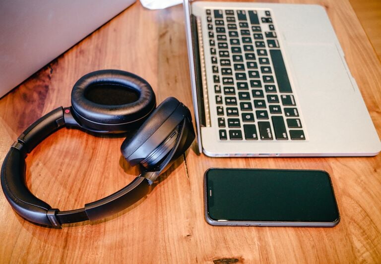 a laptop, a mobile phone and some headphones on a table