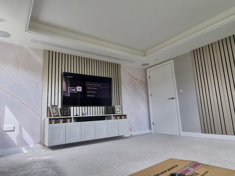 Bespoke wood slat acoustic panelling with integrated LED backlighting around a flush-mounted TV