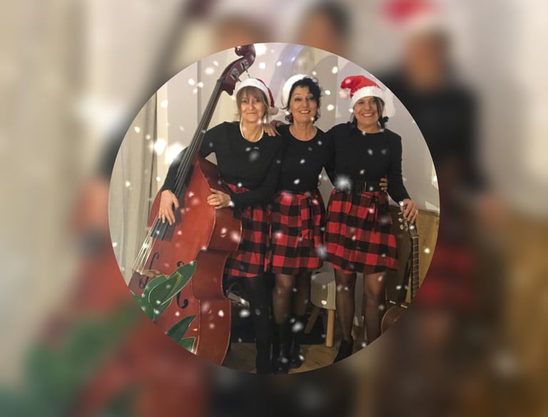 trois femmes en robe rouge et noire à carreaux et des bonnets de père Noël avec une guitare et une c