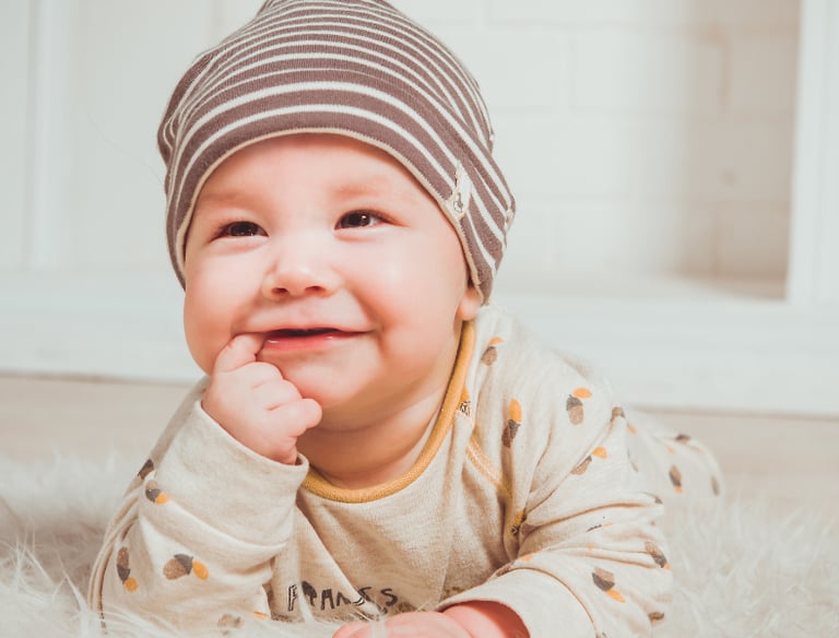 a baby is smiling and laying on a rug
