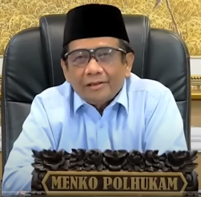 a man in a blue shirt and glasses sitting at a desk